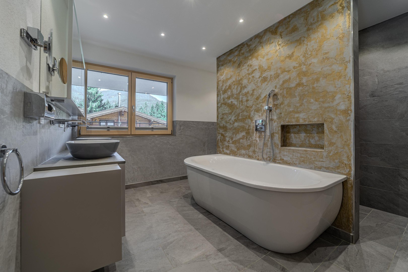 Masterbad mit freistehender Wanne vor Goldwand