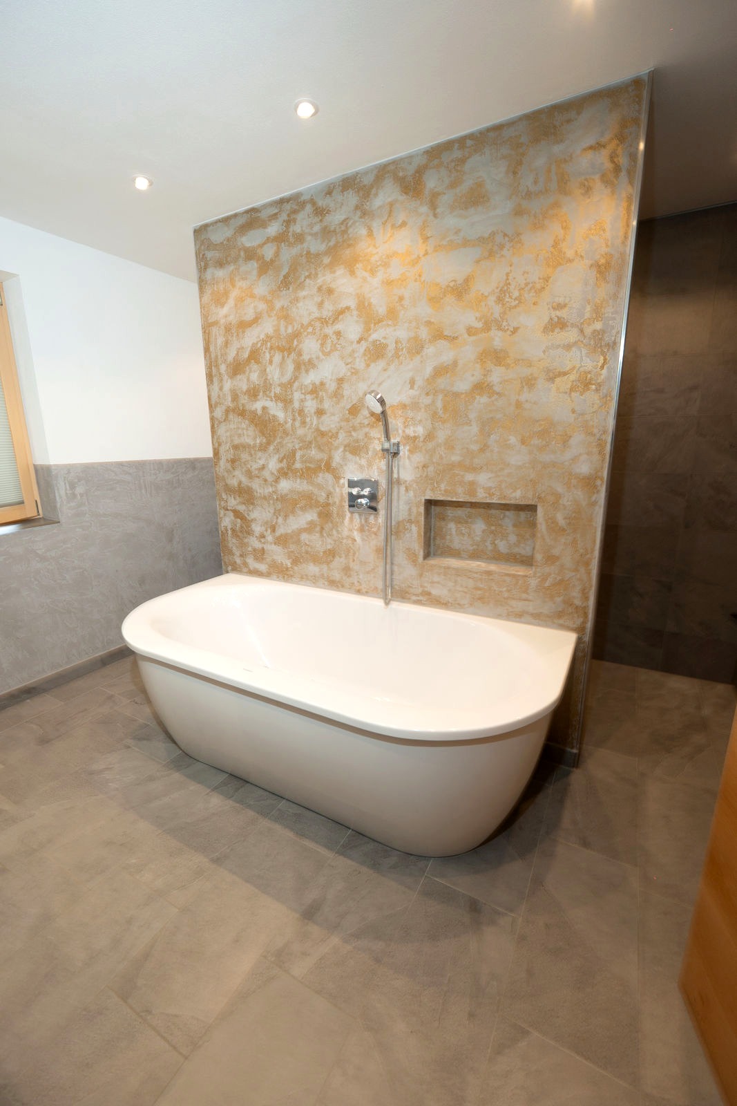 Freistehende Wanne vor handgespachtelter Goldwand